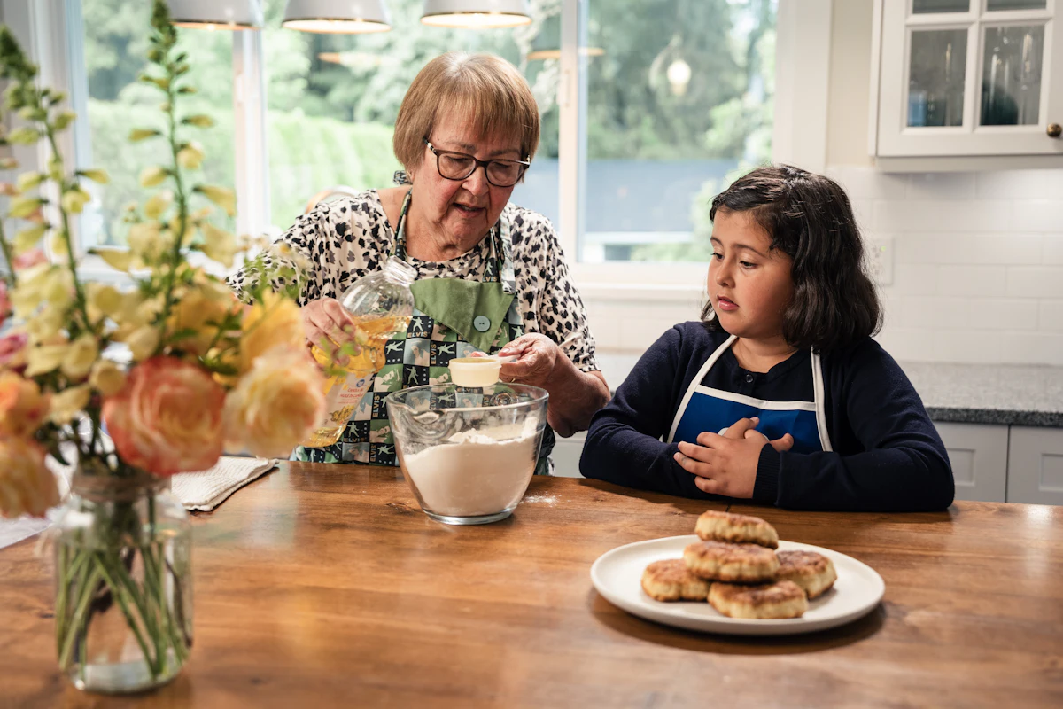 Abuela y nieta compartiendo la merienda en la mesa de la cocina
