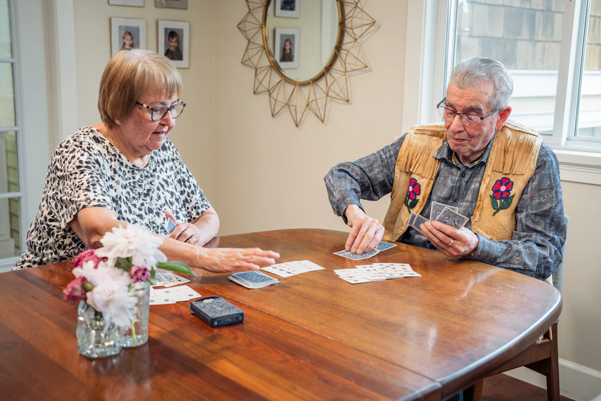 Dos personas mayores jugando a las cartas en la mesa del salón