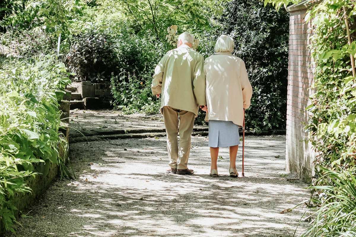 Pareja de personas mayores paseando por un camino entre árboles