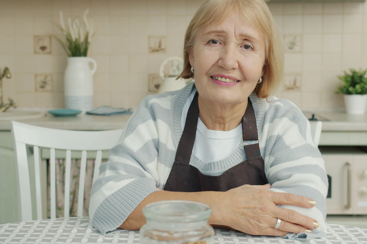 Señora mayor sonriendo sentada a la mesa de su cocina