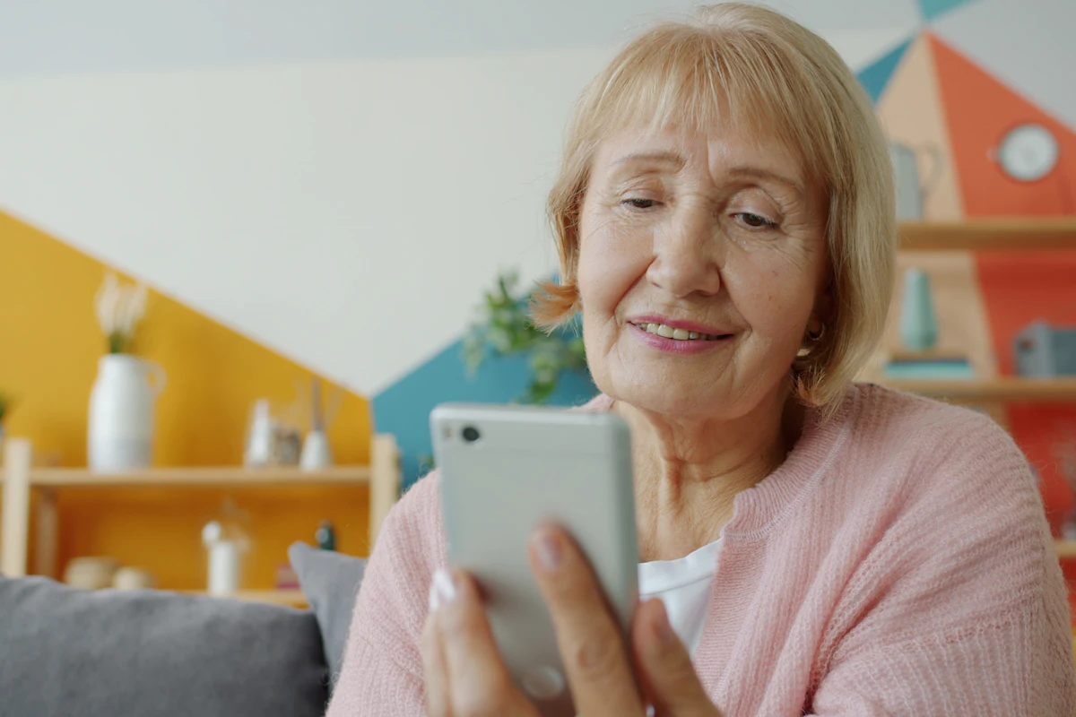 Señora mayor sonriendo mientras mira su teléfono móvil